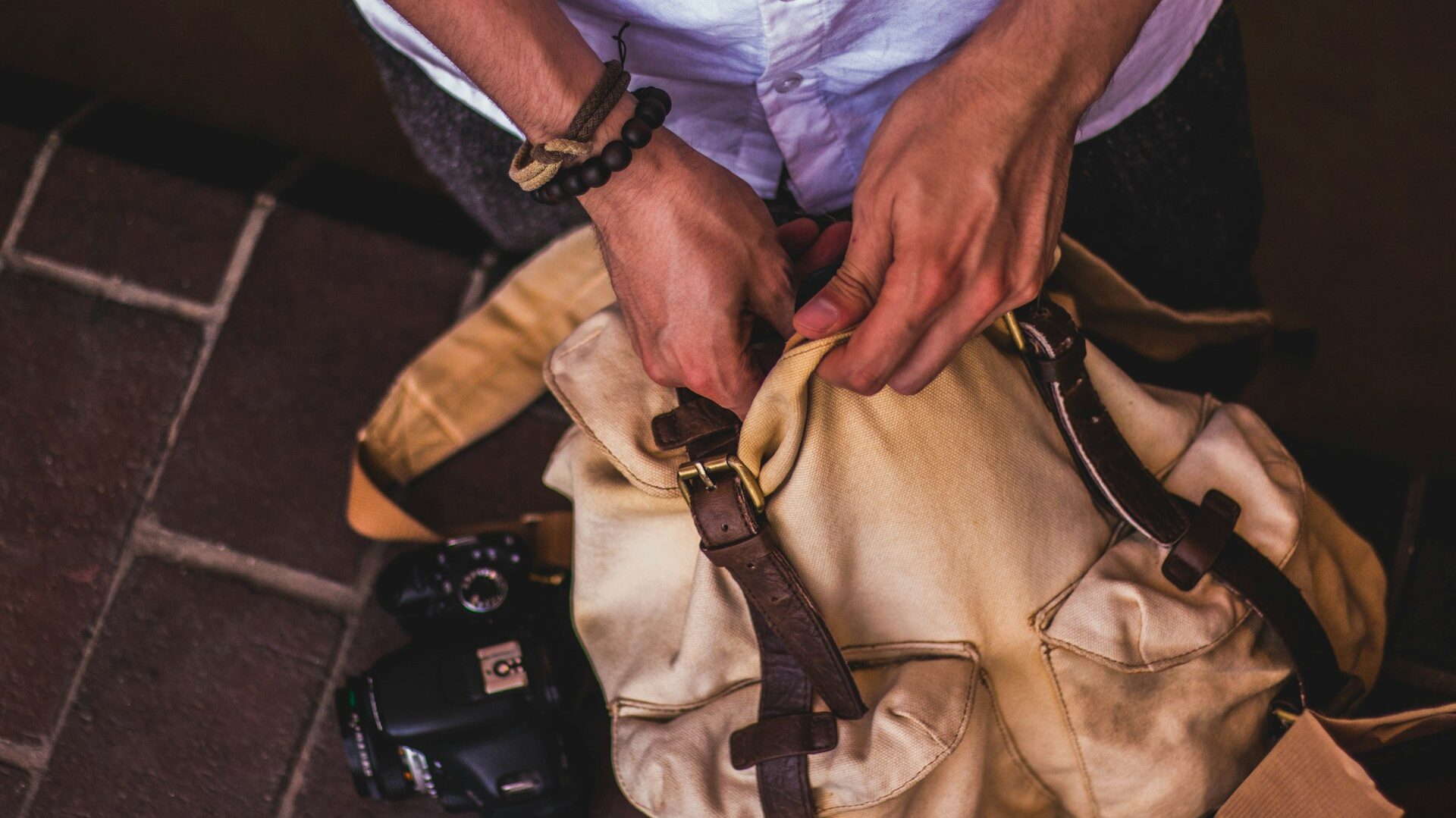 A man packing items into his backpack, highlighting the importance of packing sustainably.