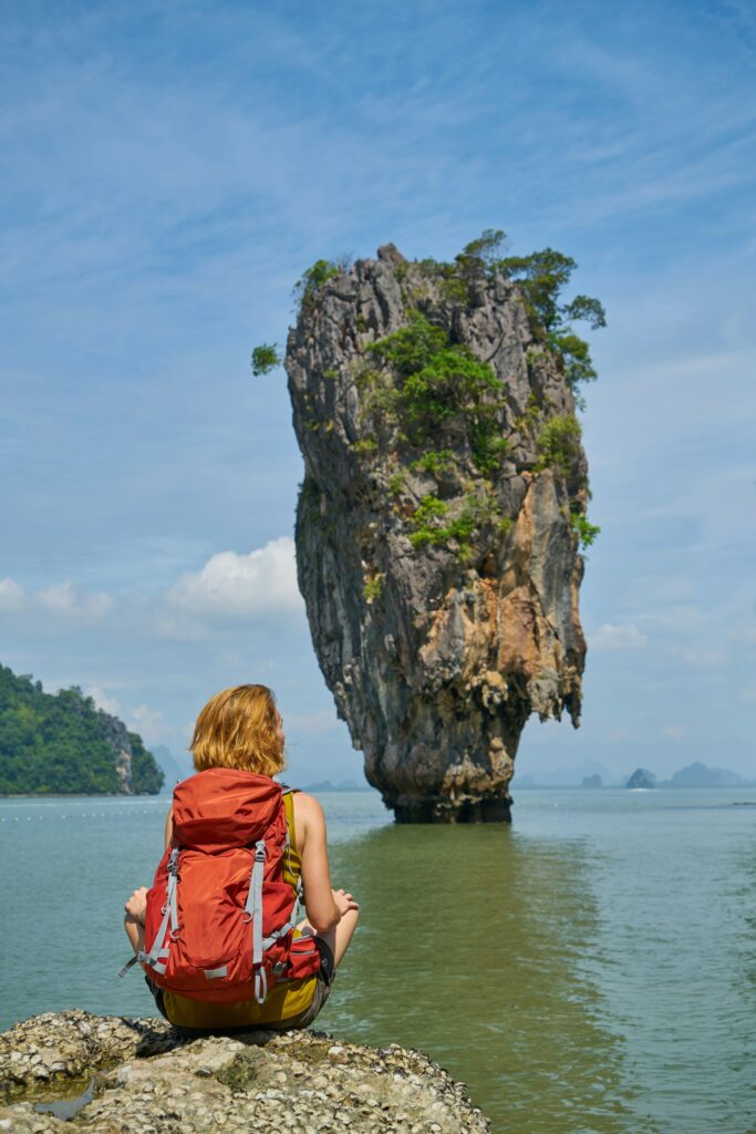 A traveling woman on a rock, sitting down.